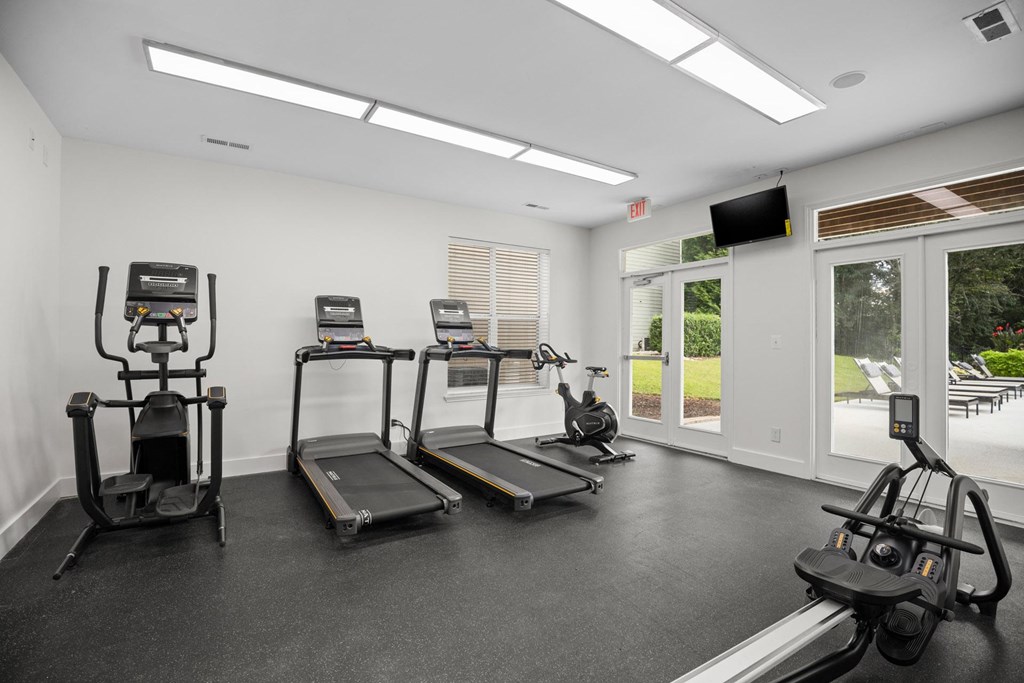A spacious gym with treadmills, elliptical machines, and a television.