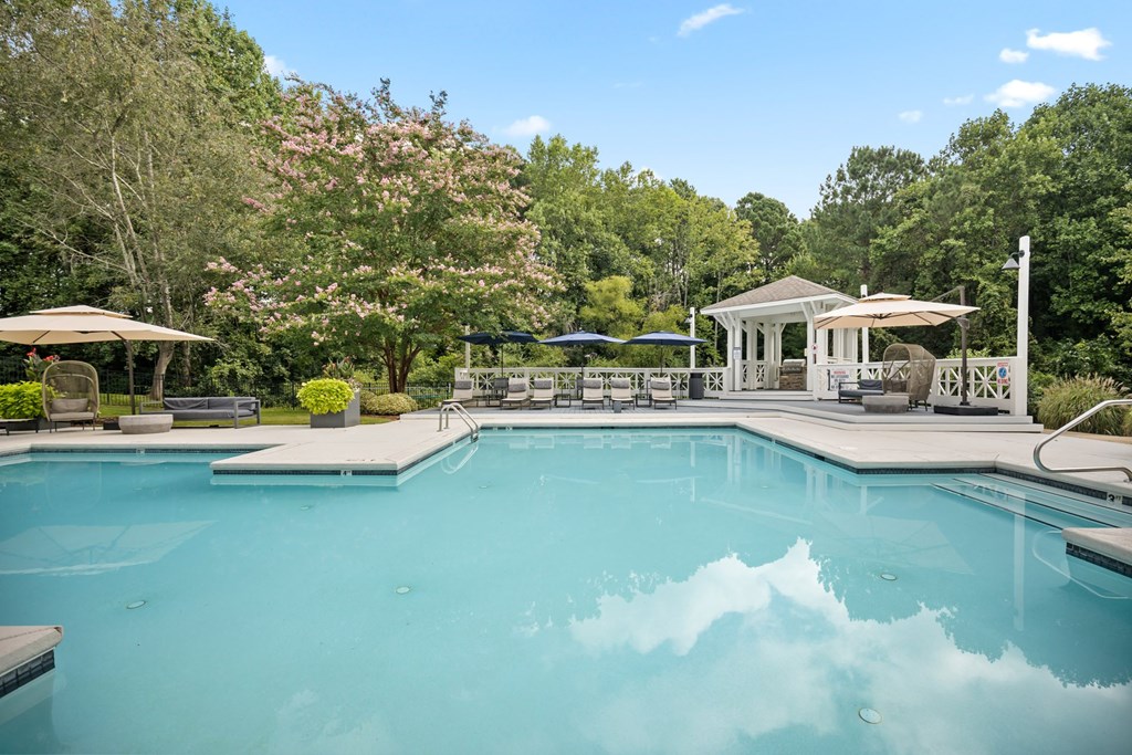 A large swimming pool surrounded by trees and a gazebo.