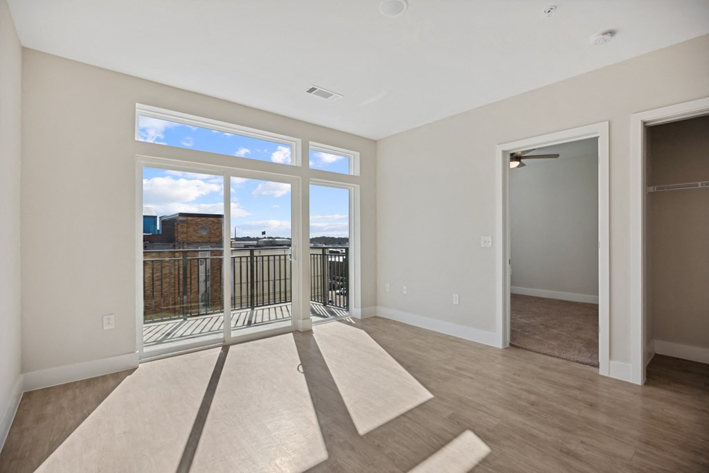 an empty living room with a large window and a door to a balconyat Centro at Pine Nash, Wilson, 27893
