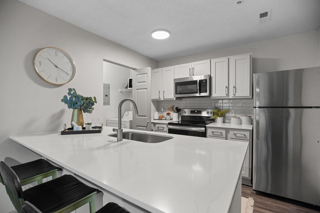 A modern kitchen with a white countertop and stainless steel appliances.