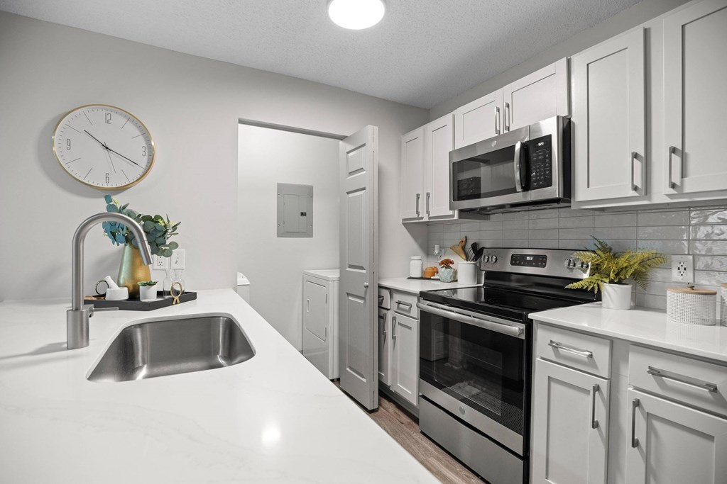 A modern kitchen with white cabinets and stainless steel appliances.