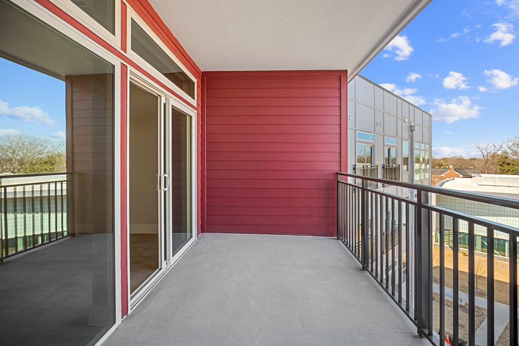 a balcony with a metal railing and a red building with glass doorsat Centro at Pine Nash, North Carolina