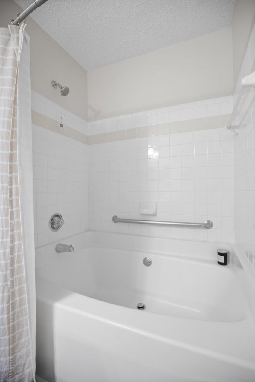 A white bathtub with a shower curtain on the left side.