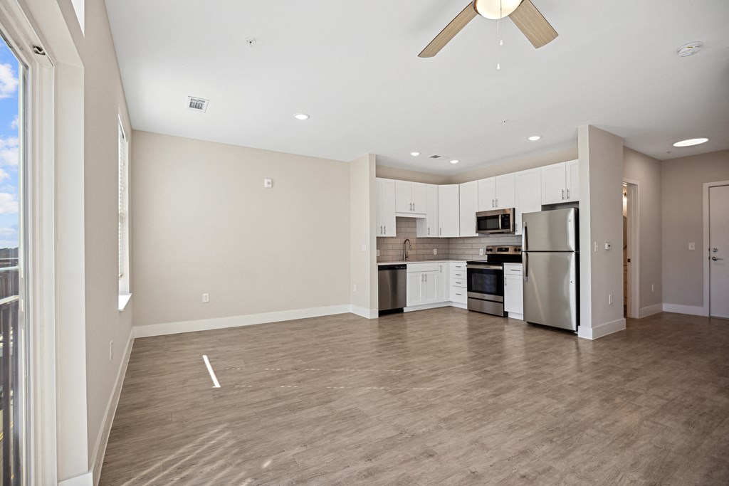 an empty living room with a kitchen and a ceiling fanat Centro at Pine Nash, Wilson, 27893