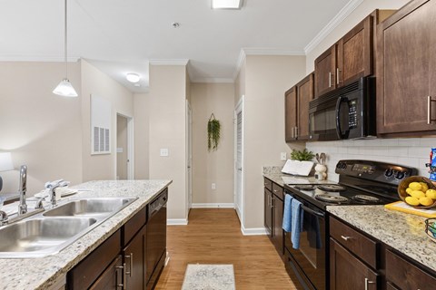 A kitchen with dark wood cabinets and a granite counter top.