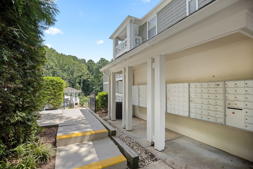 A row of mailboxes are on the sidewalk in front of a building.