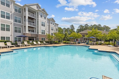 A large swimming pool in front of a multi-story apartment building.
