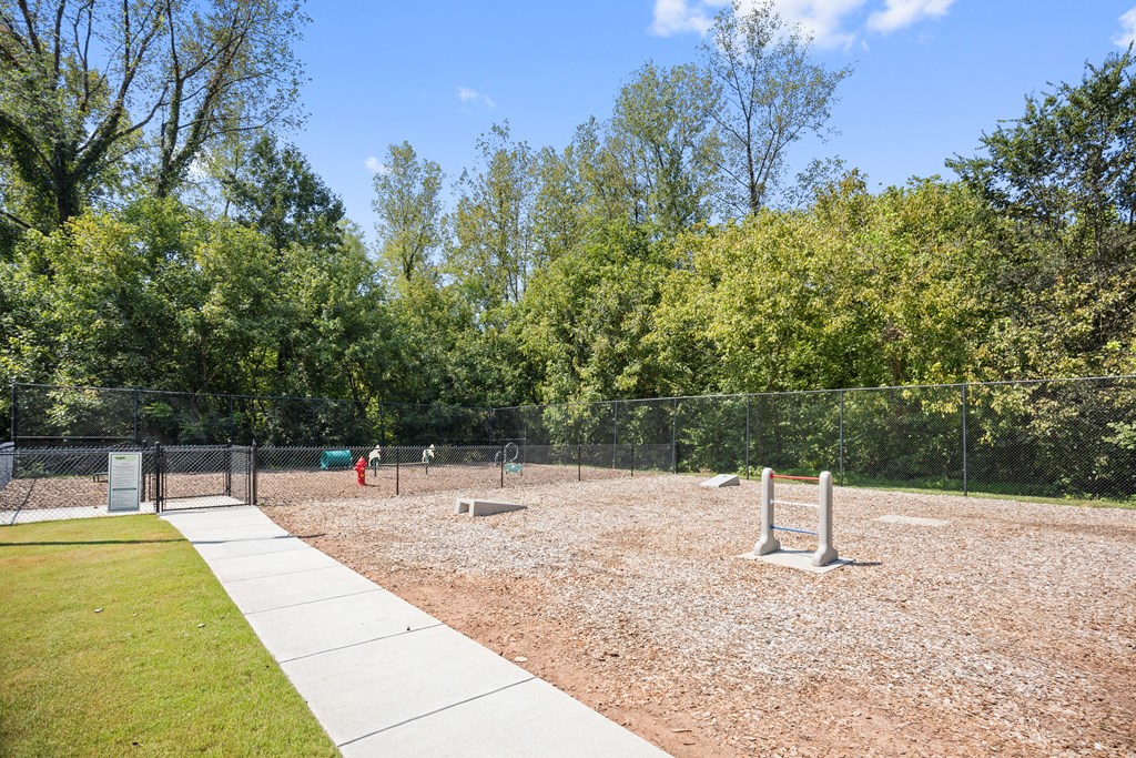 a fenced in dog park with a playground and trees