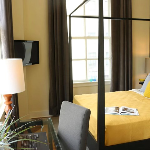 A bedroom with a bed, chair, and a lamp.