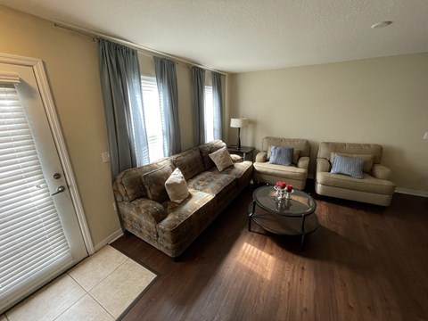 A living room with a couch, two armchairs, and a coffee table.
