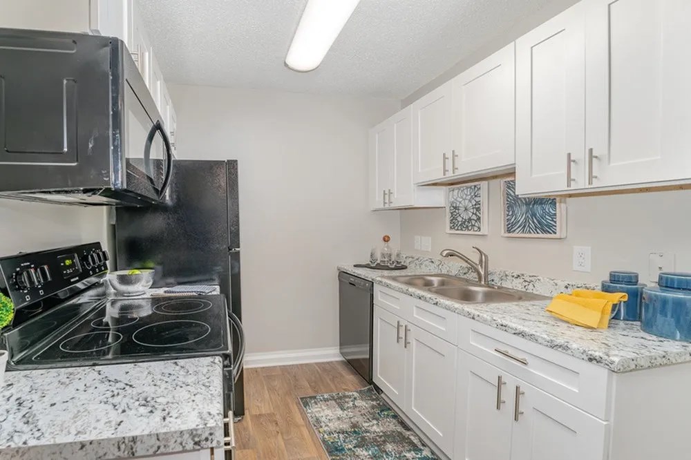 a kitchen with white cabinets and a stove and a sink at Village 1373, North Carolina