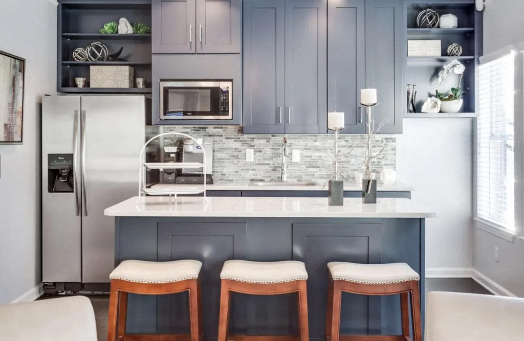 a kitchen with a counter and three bar stools  at Midtown Crossing, Raleigh