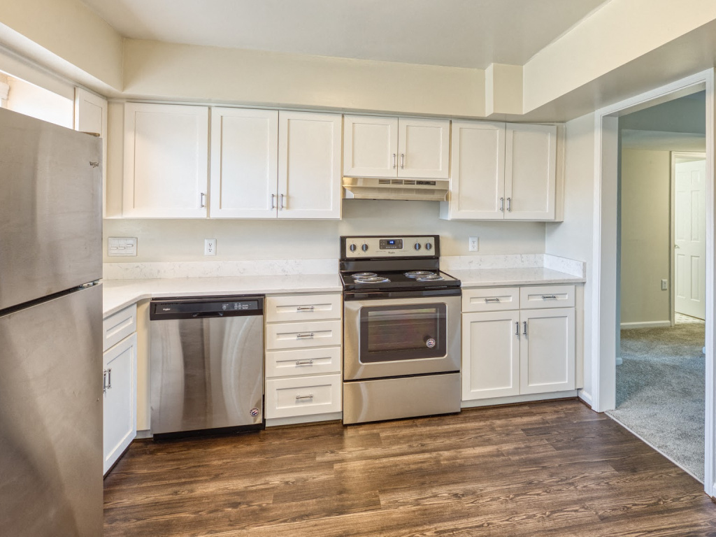 A kitchen with white cabinets and a wooden floor.