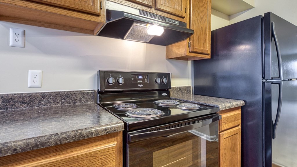 A kitchen with a black stove top oven and a black refrigerator.