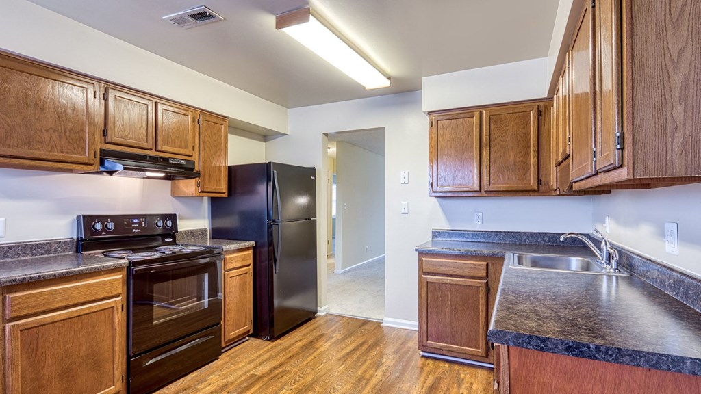 A kitchen with wooden cabinets and a black refrigerator.