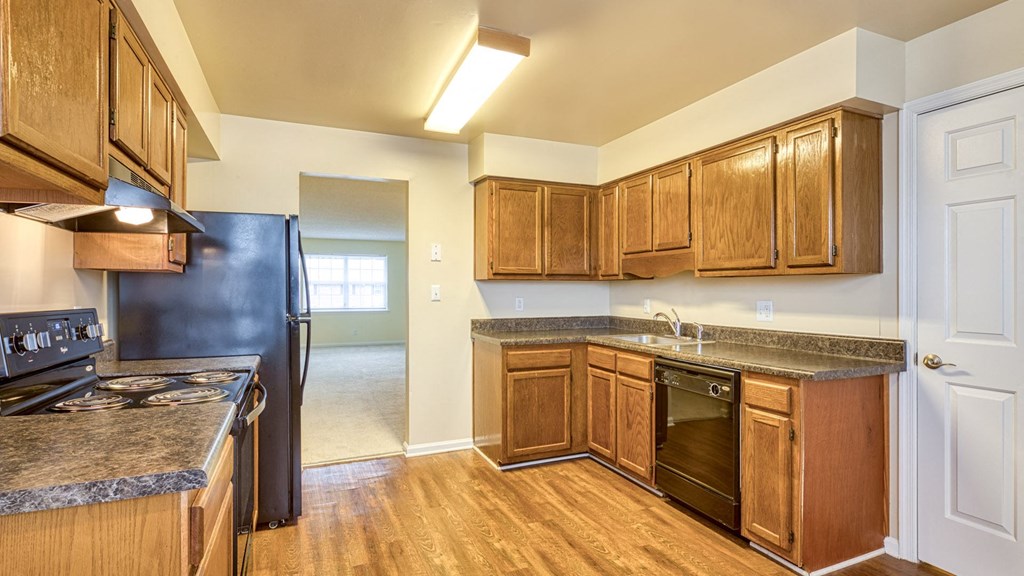 A kitchen with wooden cabinets and a black refrigerator.