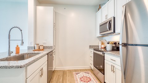 a renovated kitchen with granite counter tops and white cabinets and stainless steel appliances at Allure at Edinburgh, Chesapeake, VA, 23322