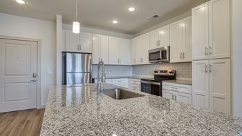 an open kitchen with granite counter tops and white cabinets at The Walker Virginia Center, Glen Allen, VA, 23059