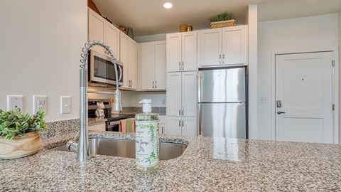 a kitchen with granite counter tops and a stainless steel refrigerator at Allure at Edinburgh, Virginia