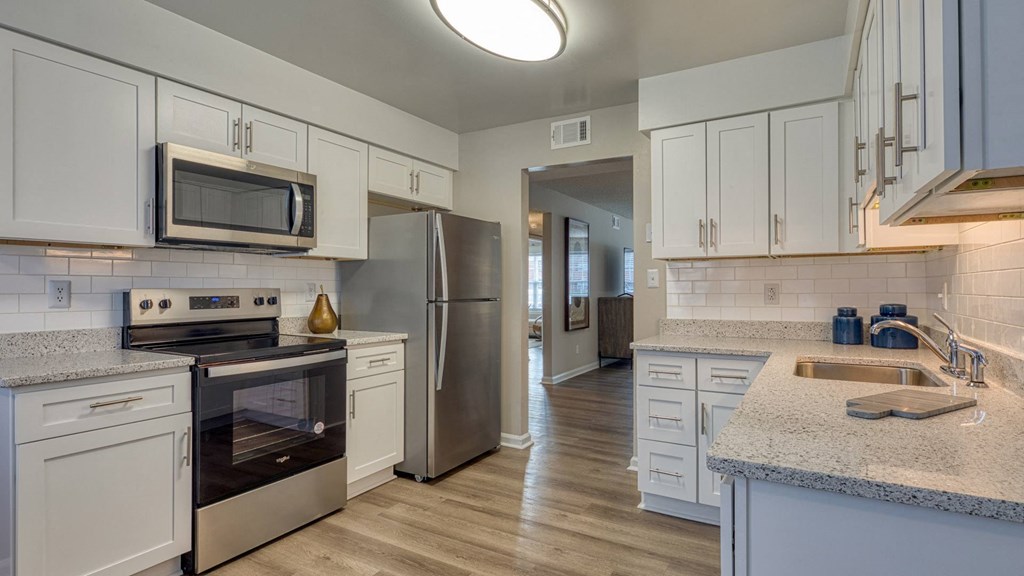 A kitchen with white cabinets and a stainless steel refrigerator.