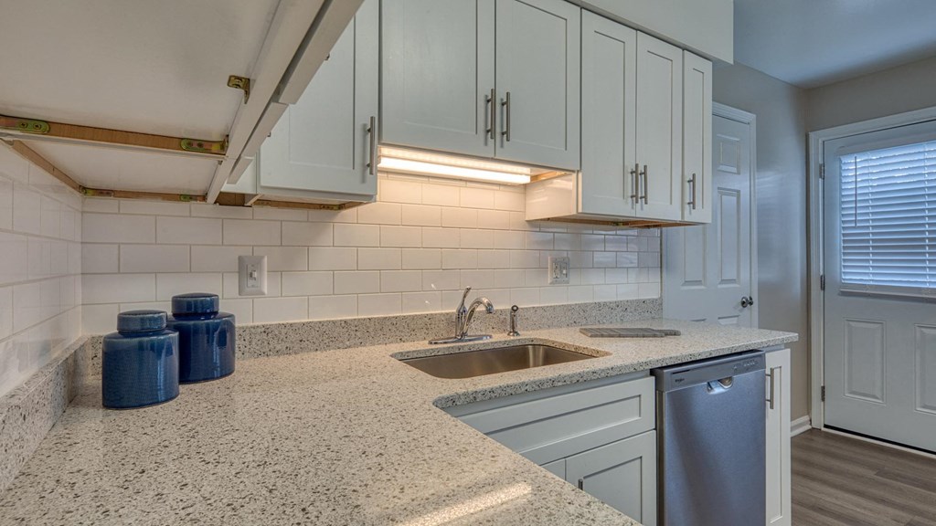 A kitchen with a granite countertop and a stainless steel dishwasher.