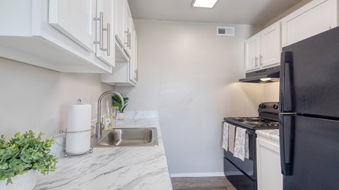 a kitchen with white cabinets and black appliances and a sink