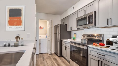A modern kitchen with a refrigerator, oven, and microwave.