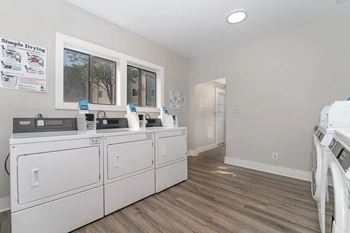 a laundry room with two washers and dryers and a door to a hallway at Village 1373, Greensboro, NC 27455