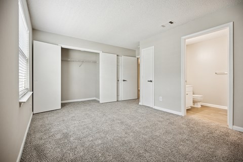 A sparsely furnished bedroom with a carpeted floor.