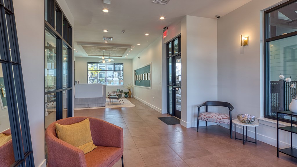a lobby with a couch and a chair and a hallway with glass doors