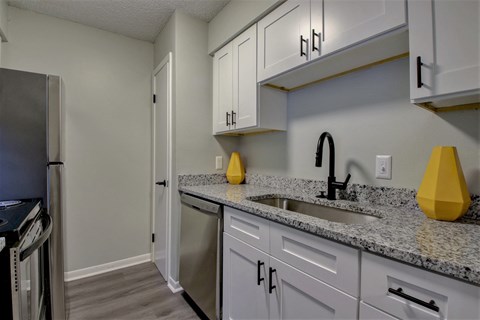 A kitchen with granite countertops and white cabinets.