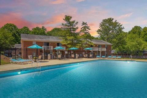 A large swimming pool in front of a building with a sunset in the background.