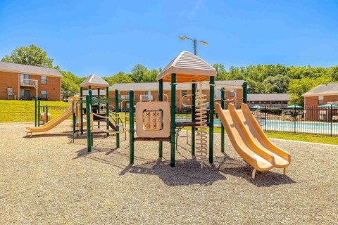 A playground with a yellow slide and a green and brown play structure.