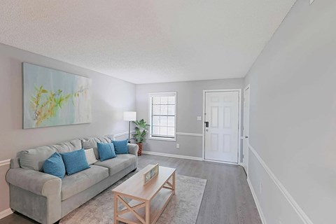 A living room with a grey couch and a painting on the wall.