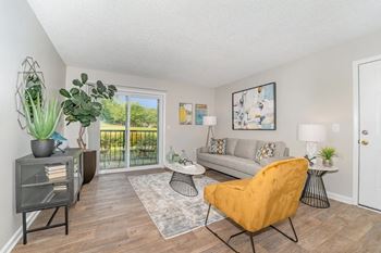 a living room with a couch and a door to a balcony at Village 1373, Greensboro, 27455