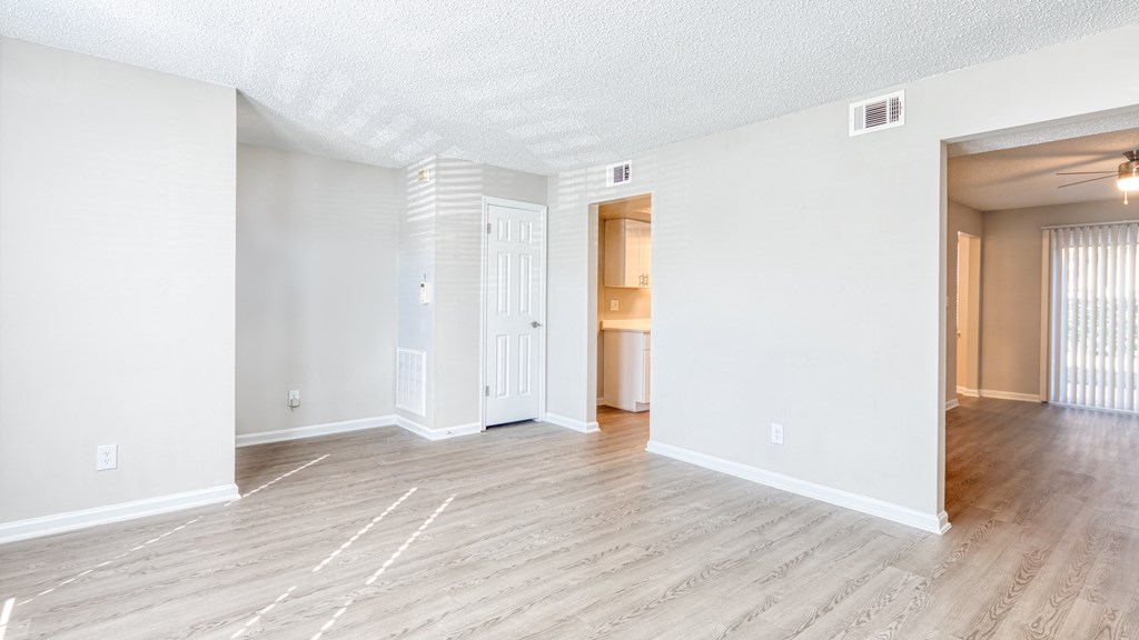 the living room and dining room of an apartment with wood flooring