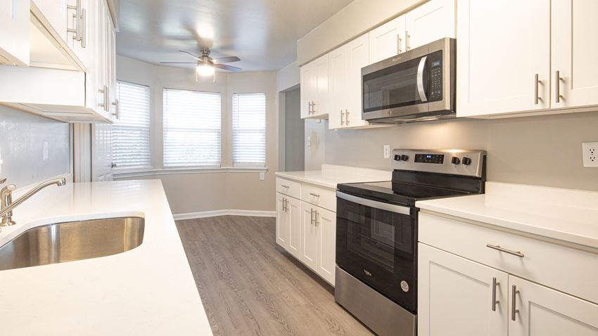 a kitchen with white cabinets and black appliances and a ceiling fan