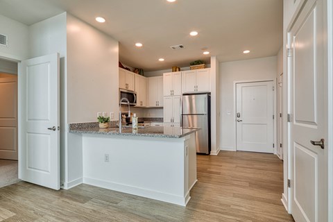 a kitchen with white cabinets and a granite counter top and a refrigerator at Allure at Edinburgh, Virginia