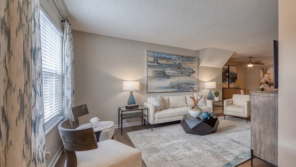 A living room with a large painting on the wall and a white couch.