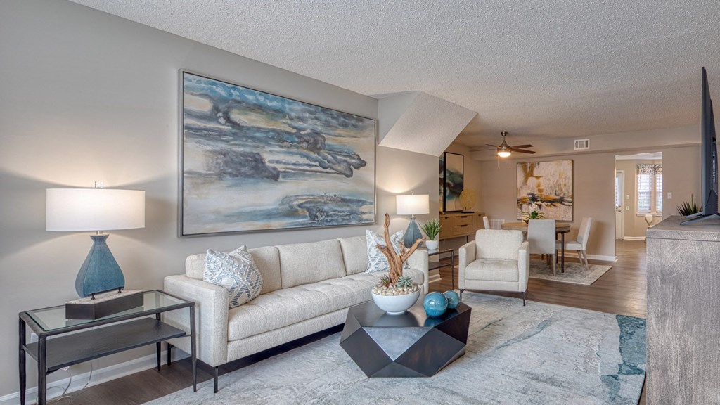 A living room with a large painting on the wall and a white couch.