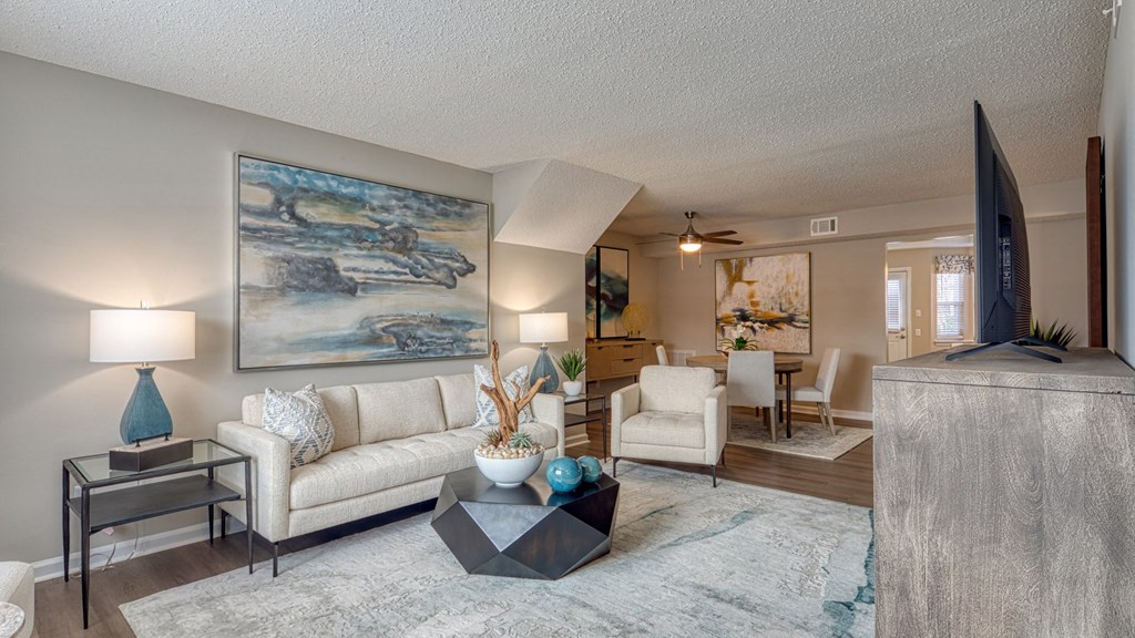 A living room with a large painting on the wall and a white couch.