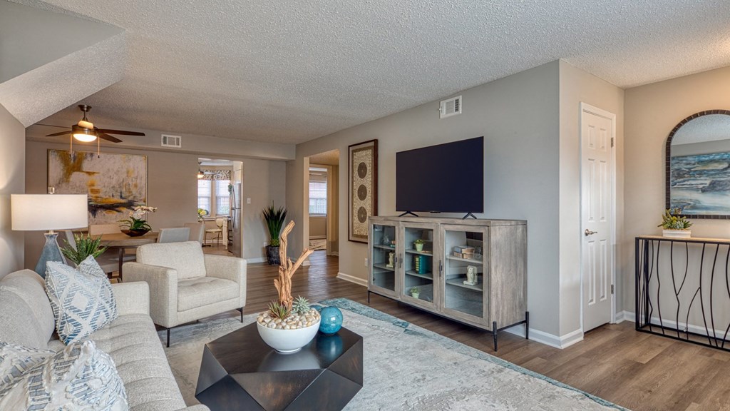 A living room with a white couch, a black coffee table, and a television.