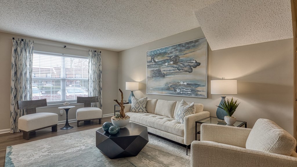 A living room with a large painting on the wall and a white sofa.