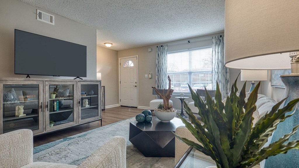 A living room with a flat screen TV and a glass table.