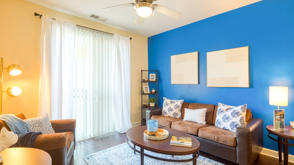 a living room with a blue wall and a couch and a table at Proximity at ODU, Norfolk, Virginia