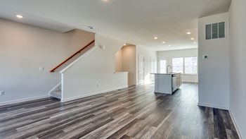 A spacious room with wooden flooring and a staircase at The Mark Townhomes Apartments, Harrisonburg, VA