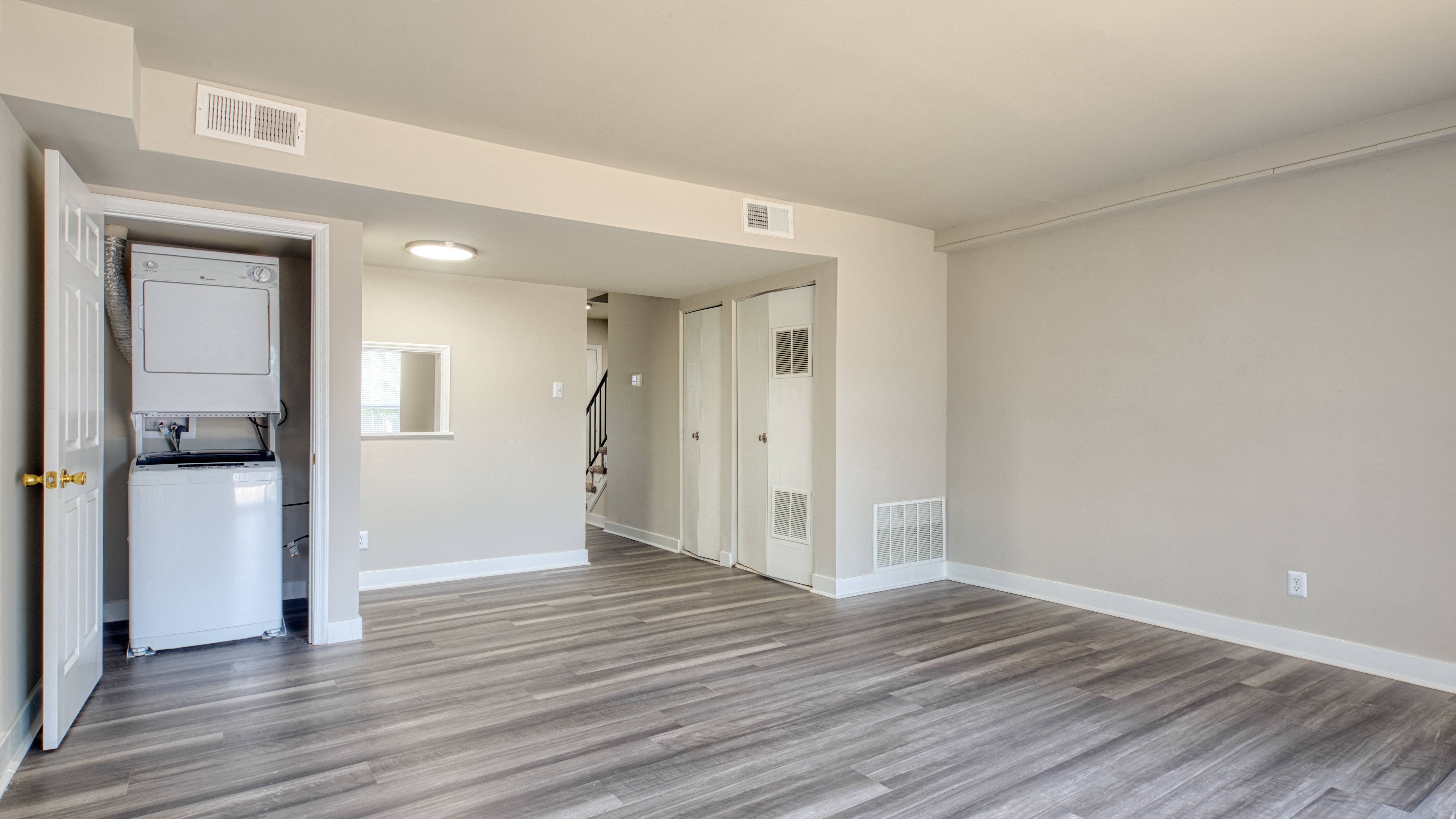 an empty living room with a refrigerator and a washer and dryer