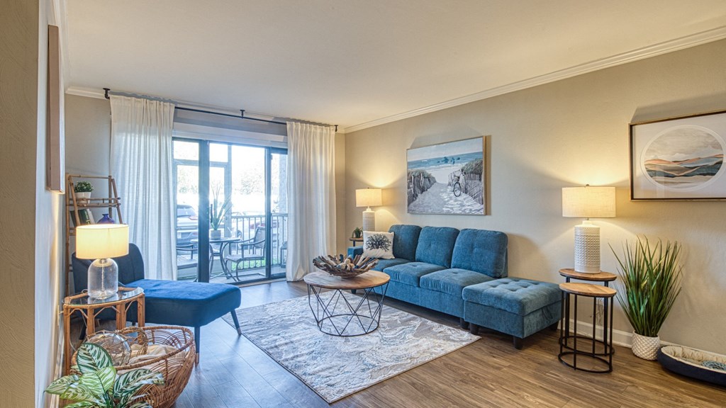 a living room with a blue couch and a sliding glass door to a balcony