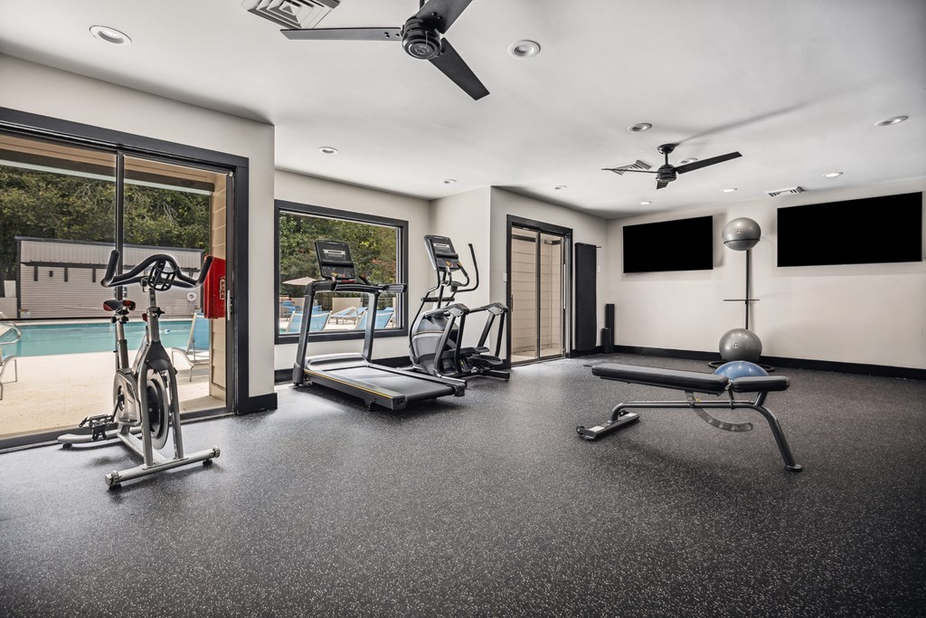 a home gym with a pool in the background