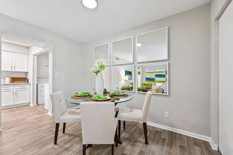 A dining room with a table set for two and a kitchen area in the background.